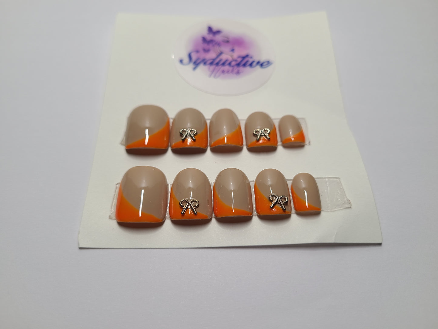 Orange and nude with gold gem bows on the index and ring fingers. Short Square, (14 pieces) Press-On Nails including Prep Kit (PN000044)