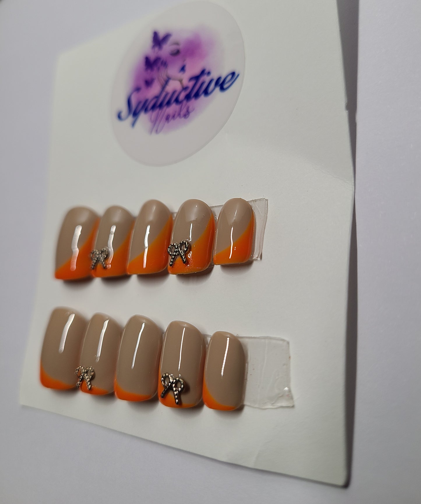 Orange and nude with gold gem bows on the index and ring fingers. Short Square, (14 pieces) Press-On Nails including Prep Kit (PN000044)