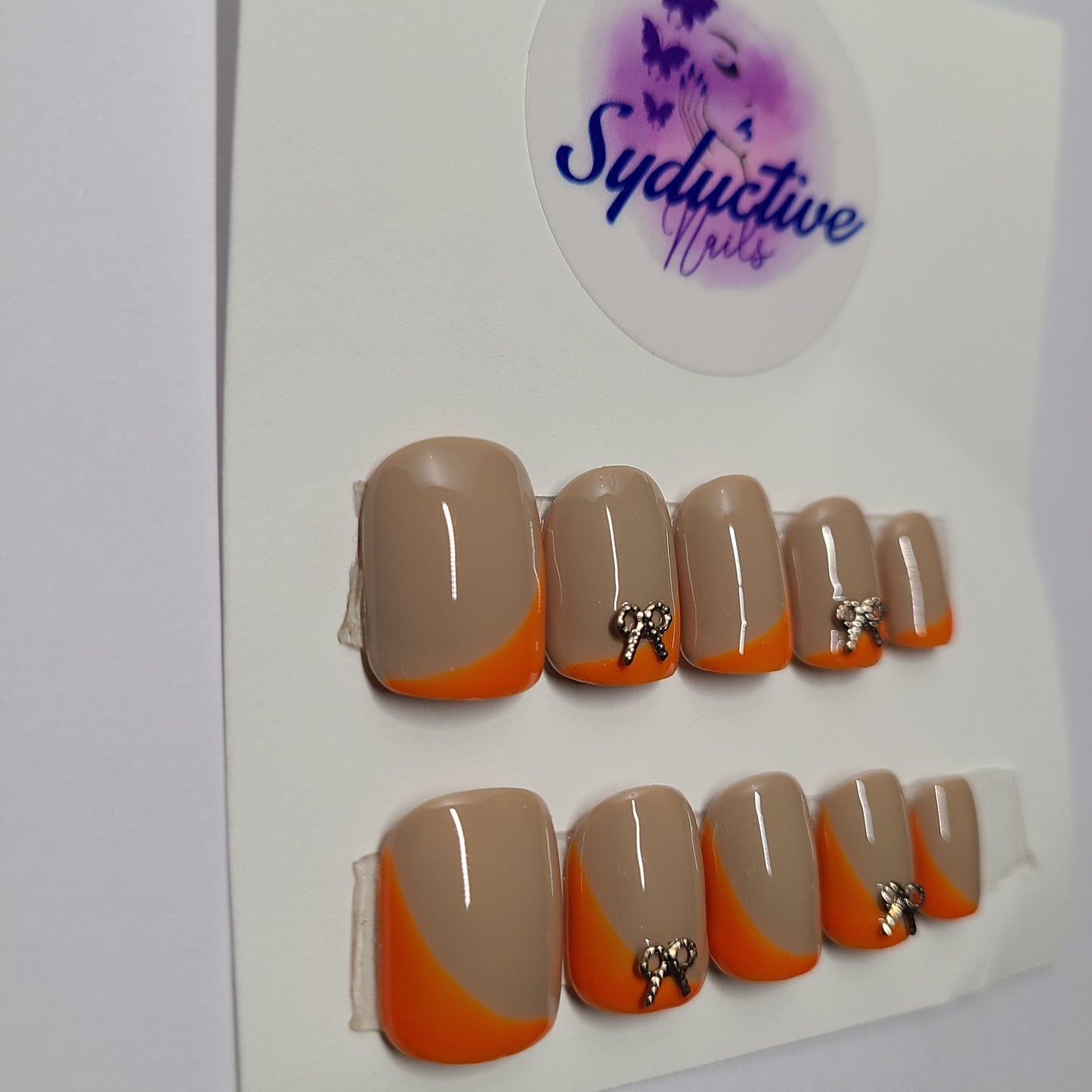 Orange and nude with gold gem bows on the index and ring fingers. Short Square, (14 pieces) Press-On Nails including Prep Kit (PN000044)